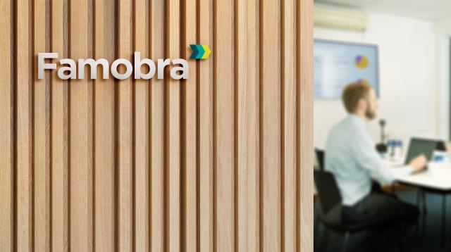 Image of office wall made from wood with the Famobra logo on. Person working on right hand side